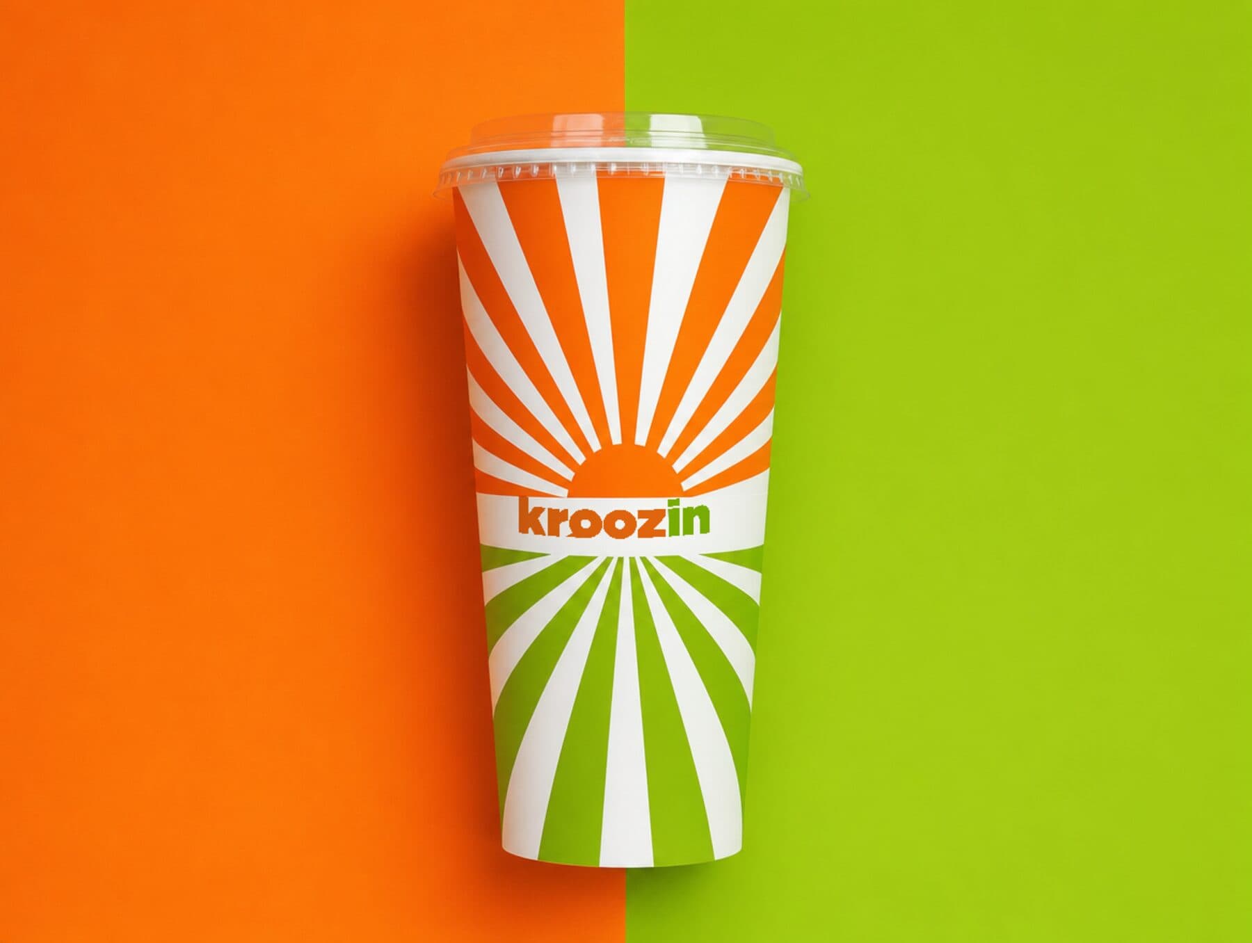A Kroozin 44oz cup in the orange and green sunburst wrap, against a split orange and green field.